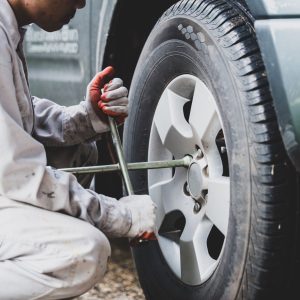 Car repairman wearing a white uniform standing and holding a wrench that is an essential tool for a mechanic